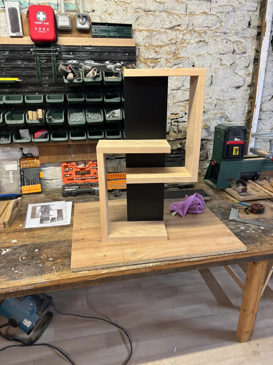 Étagère en bois clair et noir réalisée à l’atelier, posée sur un établi
